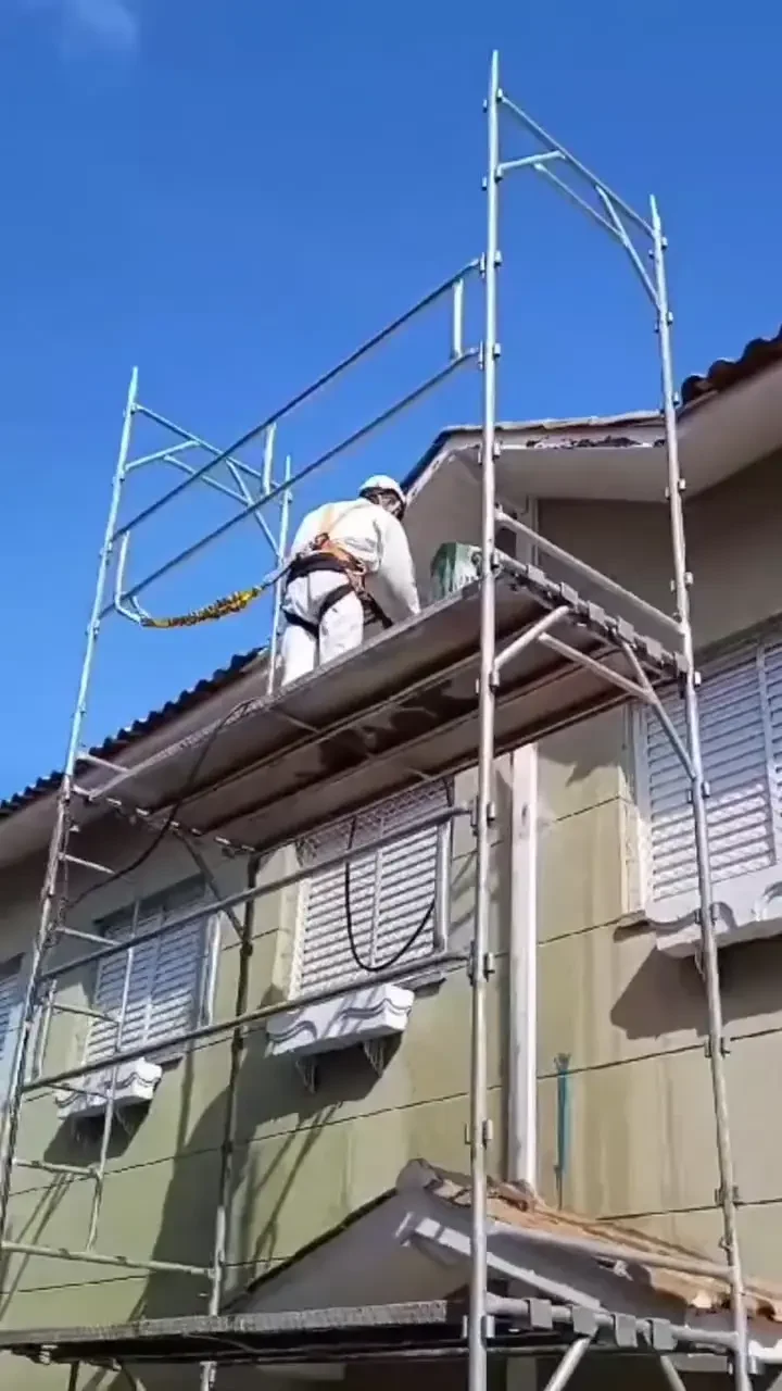 Trabalhador em fachada com acesso por andaime, em registro da Guerra Pinturas